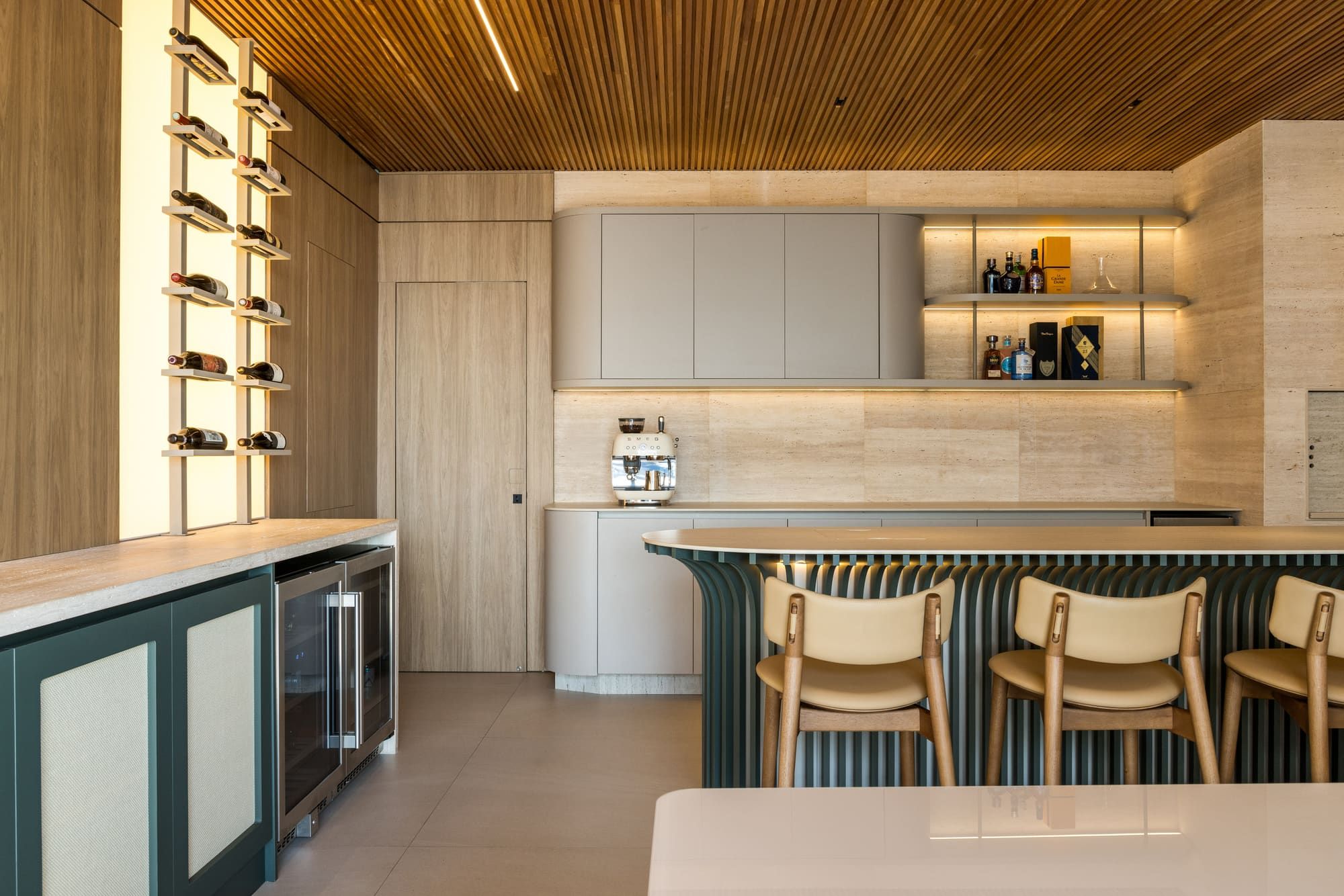Kitchen with a green fluted island, travertine walls and a slatted wood ceiling