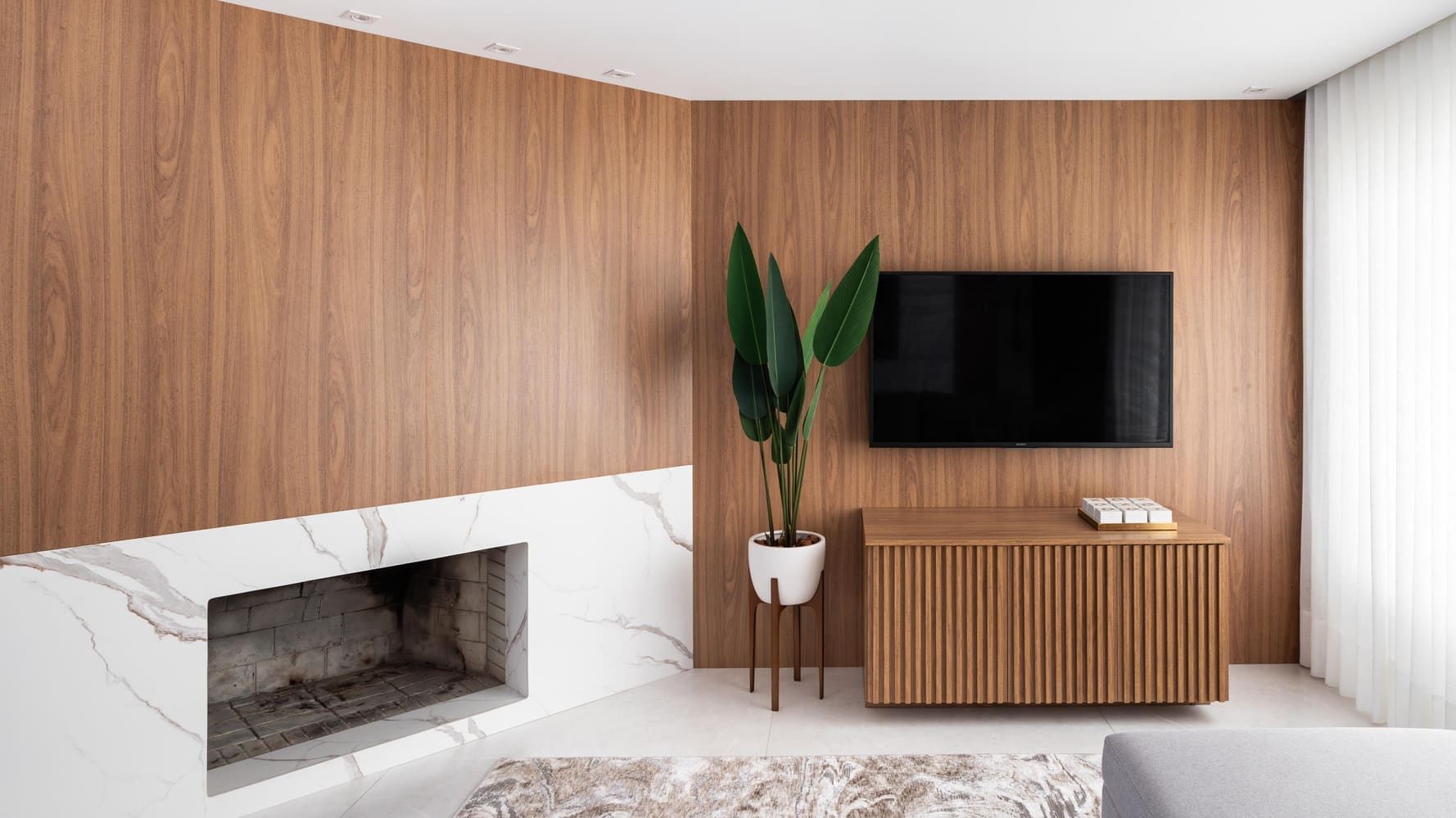 Living room with full-height wood paneling, a stone fireplace and a fluted sideboard