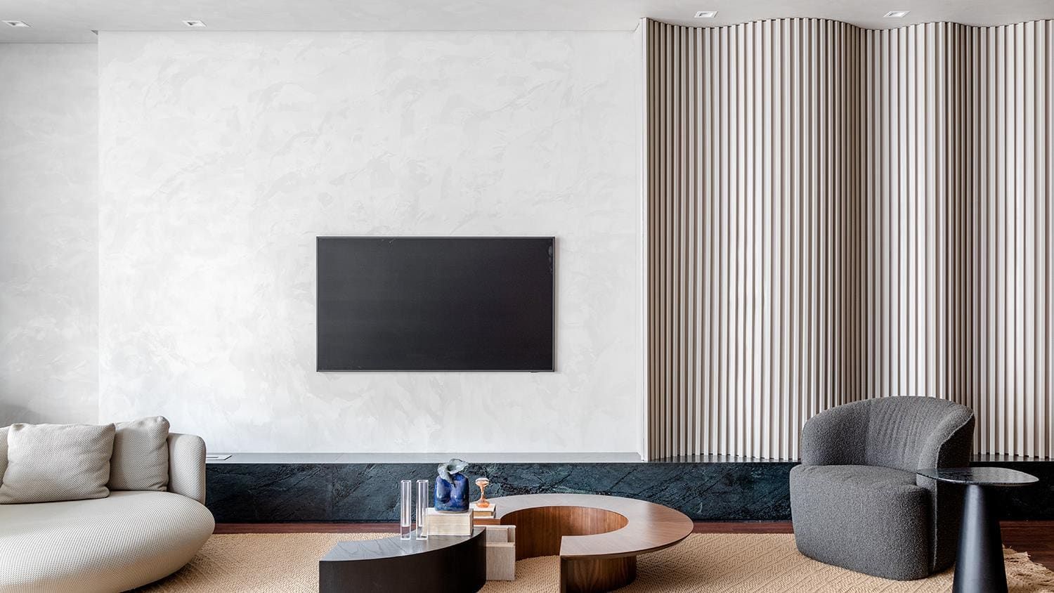 Living room with a plaster media wall framed by fluted wood and curved seating